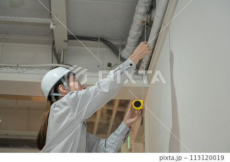 巻き尺で長さを計測するエンジニアの女性 113120019