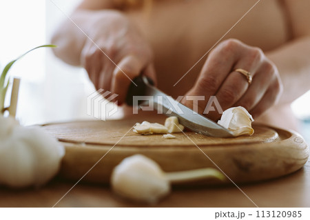 cooking, slicing garlic cloves on wooden cutting board cooking, slicing garlic cloves on wooden cutting board 113120985