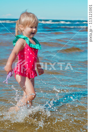 Girl of European appearance having fun in water on the beach and splashing 113121001