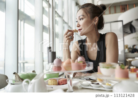 asian woman enjoying afternoon tea in luxurious hotel 113121428