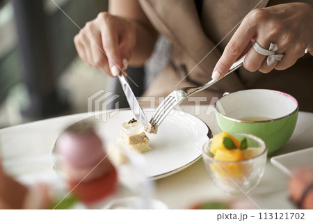woman eating dessert using fork and knife in restaurant 113121702
