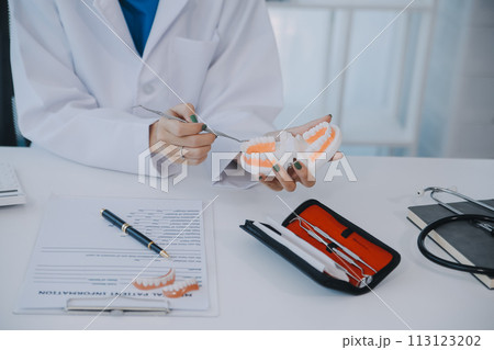 Dentists are discussing dental problems at report x-ray image on laptop screen to patients. 113123202