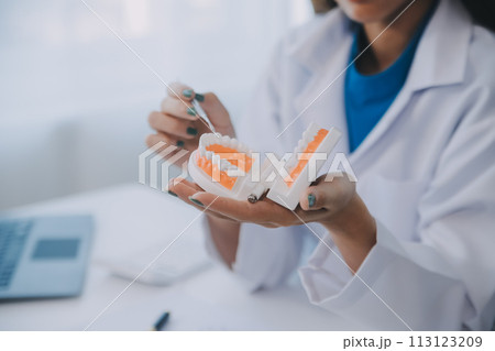 Dentists are discussing dental problems at report x-ray image on laptop screen to patients. 113123209