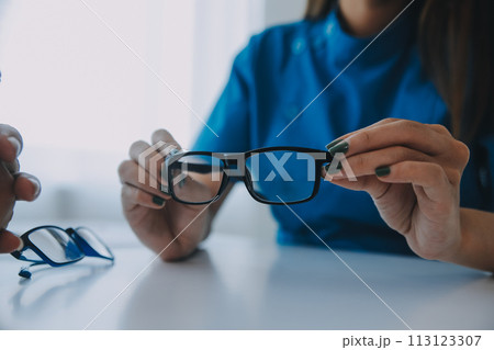 Close-up of Asian female doctor talking with elderly patient showing eyeball model and explaining eye disease in hospital 113123307
