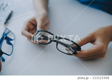 Close-up of Asian female doctor talking with elderly patient showing eyeball model and explaining eye disease in hospital 113123308