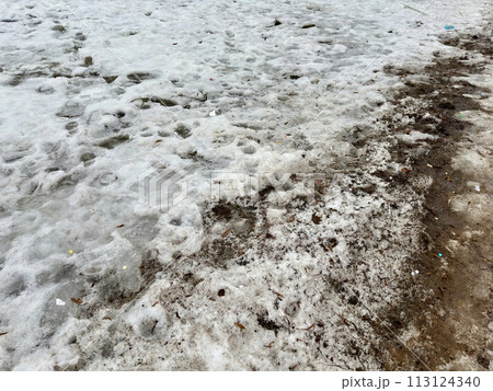 Melting dirty snow on the streets of the city during the daytime in winter. Snow with sand and mud lies on the road. Melting dirty snow on the streets of the city during the daytime in winter. Snow with sand and mud lies on the road. 113124340