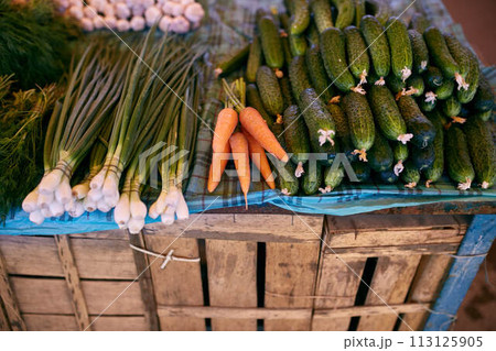 Fresh organic vegetables and fruits on sale at the local farmers summer market outdoors. Healthy organic food concept. Carrot, garlic and cucumber. 113125905