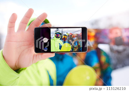 Smartphone screen with three snowboarders taking selfie at ski resort. Friends photographing for social network sharing with snowboards near forest wearing reflective goggles, colorful fashion clothes Smartphone screen with three snowboarders taking selfie at ski resort. Friends photographing for social network sharing with snowboards near forest wearing reflective goggles, colorful fashion clothes 113126210