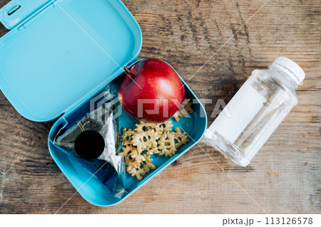 Asian student's lunchbox of onigiri,chips and apple with bottle of water,On wooden background 113126578