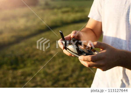 Man holds a drone remote controller in his hands. Close-up of quadrocopter RC during flight. Pilot takes aerial photos and videos with quad Man holds a drone remote controller in his hands. Close-up of quadrocopter RC during flight. Pilot takes aerial photos and videos with quad 113127644