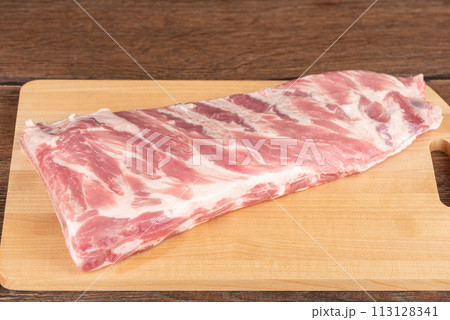Raw pork ribs on a wooden cutting board. 113128341