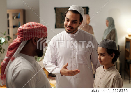 Selective focus shot of happy Muslim man introducing his son to distant relative at family gathering on Uraza Bayram day 113128373