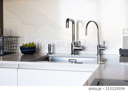 Kitchen brass utensils, chef accessories. Hanging modern kitchen with white marble wall and stone tabletop. Kitchen brass utensils, chef accessories. Hanging modern kitchen with white marble wall and stone tabletop. 113129104