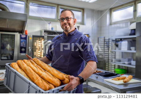 Smiling man employee holding baguettes at bakery 113129481
