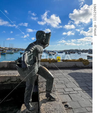 A wonderful monument on the shore of Marsaxlokk, Malta: a young son and daughter meet a father who is carrying two wicker baskets full of caught fish. A wonderful monument on the shore of Marsaxlokk, Malta: a young son and daughter meet a father who is carrying two wicker baskets full of caught fish. 113129965