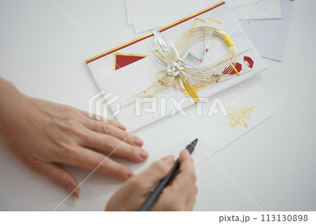 お祝いの熨斗袋に筆で名前を書くミドル女性の手元 113130898