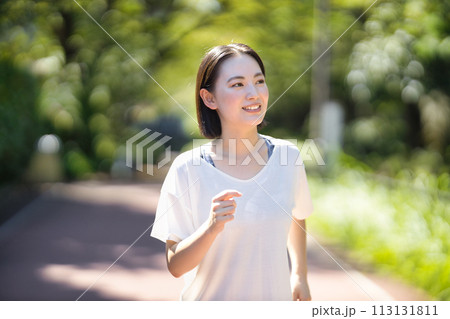 スポーツウエアでランニングをする笑顔の若い女性 113131811