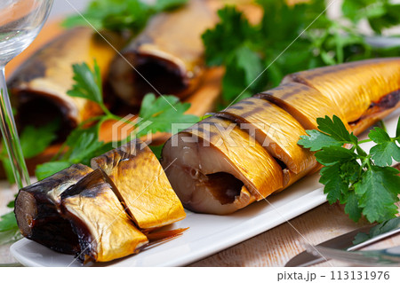 Smoked mackerel cut into pieces with parsley on a table Smoked mackerel cut into pieces with parsley on a table 113131976