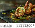 Grilled prawns on slate with lemon zest, herbs, and spices, capturing the rich essence of seafood. 113132007