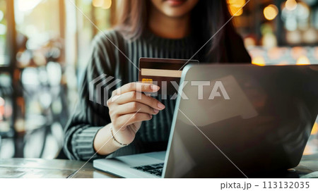 A woman is using a laptop to pay for something with a credit card 113132035