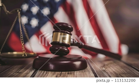 A gavel sits on a wooden surface in front of an American flag 113132200