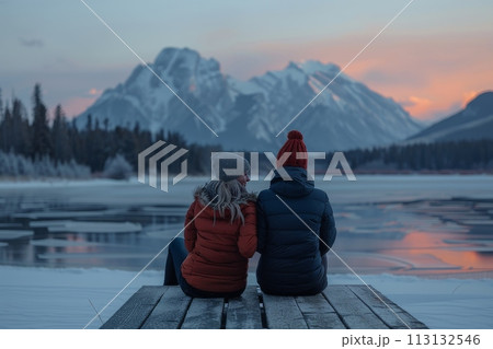 A couple is sitting on a dock overlooking a lake 113132546