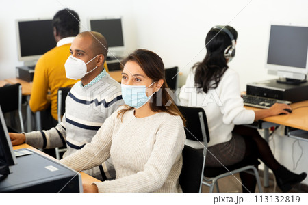 Female student in face mask working on computer in library Female student in face mask working on computer in library 113132819