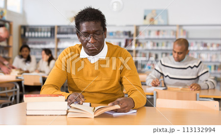 Young adult man studying in public library 113132994