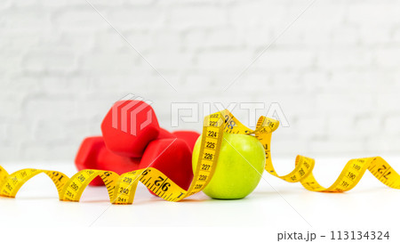 Close up green apple and dumbbell. Healthy snack for diet planning. Fresh fruit with green fruit Close up green apple and dumbbell. Healthy snack for diet planning. Fresh fruit with green fruit 113134324