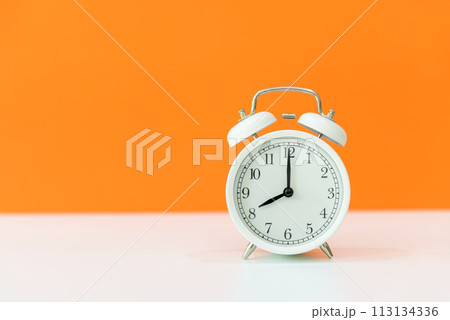 Alarm white vintage alarm clock with orange color background, copy space for text. Alarm white vintage alarm clock with orange color background, copy space for text. 113134336