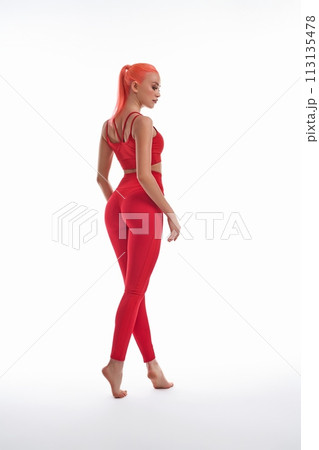 Graceful slim woman in red active wear standing on her tiptoe 113135478
