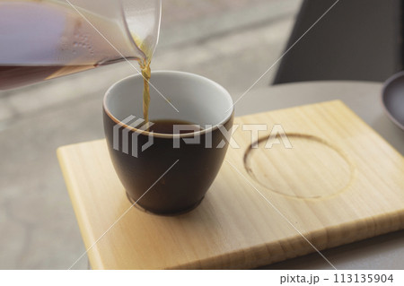 ガラス容器から注がれる木製トレーに乗ったコーヒー 113135904