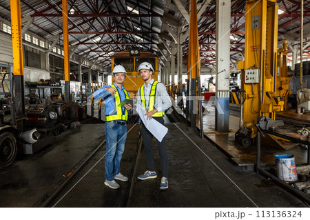 Railway technician engineer wearing safety uniform and safety helmet holding tablet and blueprint. Railway technician engineer wearing safety uniform and safety helmet holding tablet and blueprint. 113136324