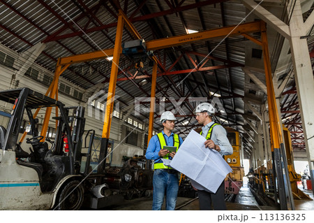 Railway technician engineer wearing safety uniform and safety helmet holding tablet and blueprint. Railway technician engineer wearing safety uniform and safety helmet holding tablet and blueprint. 113136325