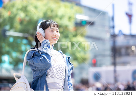 ストリートスナップ　ヘッドフォンで音楽を聴いている若い女性 113138921