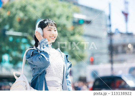 ストリートスナップ ヘッドフォンで音楽を聴いている若い女性 ストリートスナップ ヘッドフォンで音楽を聴いている若い女性 113138922