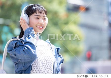ストリートスナップ　ヘッドフォンで音楽を聴いている若い女性 113138924