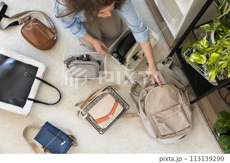 A young woman puts various women's handbags for storage in her home wardrobe. Accessories and bags. 113139290