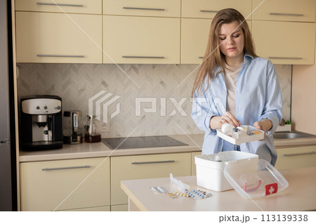 Female housewife checking medicines at domestic first aid kit neatly placing storage organization 113139338