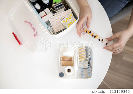 Closeup female hand placing medicament domestic first aid kit. Storage organization emergency supply 113139346