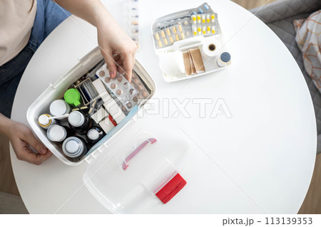 Closeup female hand placing medicament domestic first aid kit. Storage organization emergency supply Closeup female hand placing medicament domestic first aid kit. Storage organization emergency supply 113139353