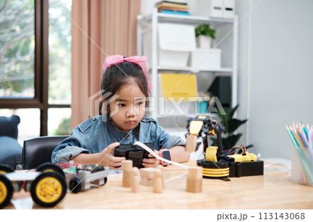A young girl is playing with a remote control a robot 113143068