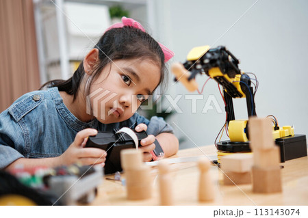 A young girl is playing with a remote control a robot 113143074