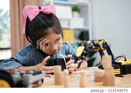 A young girl is playing with a remote control a robot 113143075