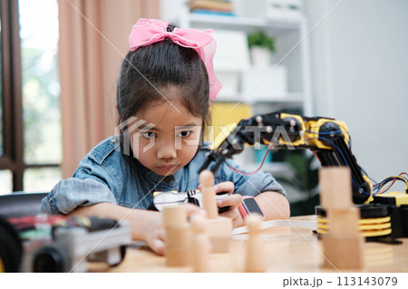 A young girl is playing with a remote control a robot 113143079