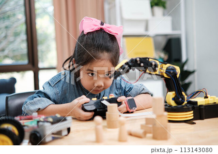 A young girl is playing with a remote control a robot A young girl is playing with a remote control a robot 113143080