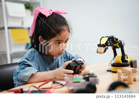 A young girl is playing with a remote control a robot A young girl is playing with a remote control a robot 113143084