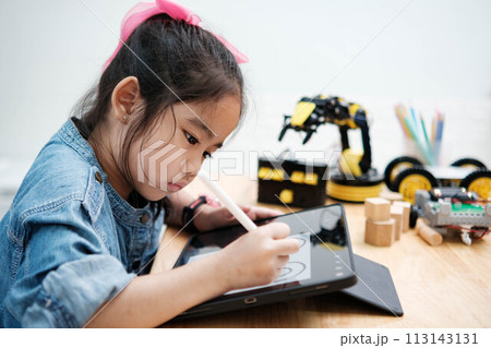 A young girl is playing with a remote control a robot 113143131