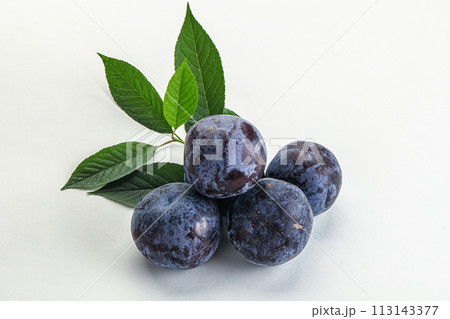 Raw purple plums heap with leaves 113143377