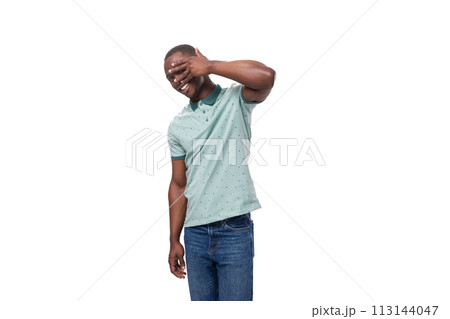 young shy african man dressed in a t-shirt and jeans stands thoughtfully 113144047